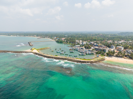Aerial view of fishing boats moored in a harbor protected by a stone breakwater along the tropical coastline of Hikkaduwa Southern Province Sri Lanka. Aerial view of fishing boats moored in a harbor protected by a stone breakwater along the tropical coastline of Hikkaduwa Southern Province Sri Lanka.