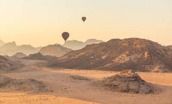 Aerial view of hot air balloons floating over the sandstone mountains and desert dunes of Wadi Rum Protected Area in Aqaba Governorate Jordan.