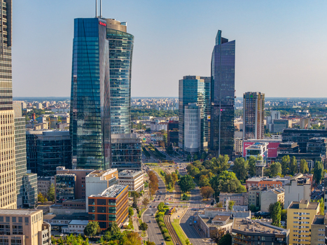 Aerial view of the modern skyline of Warsaw featuring glass skyscrapers and urban streets with tram lines and green trees in Poland. Aerial view of the modern skyline of Warsaw featuring glass skyscrapers and urban streets with tram lines and green trees in Poland.