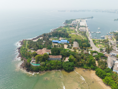 Aerial view of Dewata Beach Road and the lush coastline with a harbor and docked boats Galle Southern Province Sri Lanka.