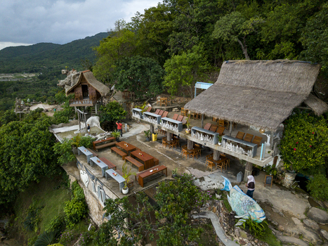 Aerial view of a wooden hut and a restaurant with a thatched roof perched atop rocky terrain amidst lush greenery Bukit Love Karimunjawa Jawa Tengah Indonesia. Aerial view of a wooden hut and a restaurant with a thatched roof perched atop rocky terrain amidst lush greenery Bukit Love Karimunjawa Jawa Tengah Indonesia.
