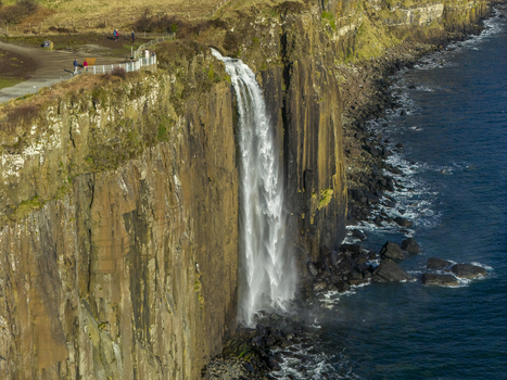 Aerial view of Kilt Rock and Mealt Falls cascading down basalt cliffs into the sea with people on the viewing platform Isle of Skye Scotland United Kingdom. Aerial view of Kilt Rock and Mealt Falls cascading down basalt cliffs into the sea with people on the viewing platform Isle of Skye Scotland United Kingdom.