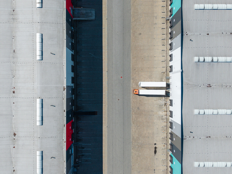 Aerial view of a modern warehouse facility with loading docks and a truck parked in the central driveway in Lielvarzi Kekava Municipality Latvia. Aerial view of a modern warehouse facility with loading docks and a truck parked in the central driveway in Lielvarzi Kekava Municipality Latvia.