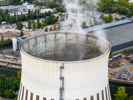 Aerial view of the cooling tower at Heizkraftwerk Reuter West emitting steam surrounded by industrial infrastructure and greenery in Berlin Berlin Germany.