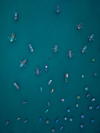 Aerial view of numerous small fishing boats scattered across the deep blue water in VIETNAM. Aerial view of numerous small fishing boats scattered across the deep blue water in VIETNAM.