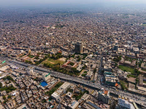 Aerial view of the historic Bala Hisar Fort surrounded by the dense urban sprawl bustling roads and rooftops of Peshawar Khyber Pakhtunkhwa Pakistan.