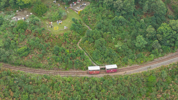 Aerial view of the Outeniqua Power Van railcar traveling along the tracks through lush green forest near Outeniqua Pass Garden Route District Municipality Western Cape South Africa.