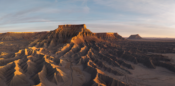 Aerial view of the rugged badlands and dramatic sandstone buttes of Caineville illuminated by golden hour light in the desert landscape of Caineville Utah United States.