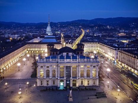 Aerial view of Palazzo Madama in Piazza Castello with the Mole Antonelliana spire illuminated against the twilight sky Turin Piedmont Italy.