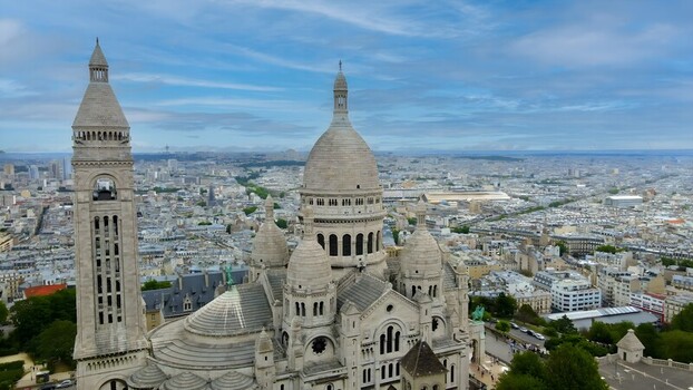 Aerial view of the Sacre Coeur Basilica with its white stone domes and bell tower overlooking the sprawling cityscape of Paris Ile de France France. Aerial view of the Sacre Coeur Basilica with its white stone domes and bell tower overlooking the sprawling cityscape of Paris Ile de France France.
