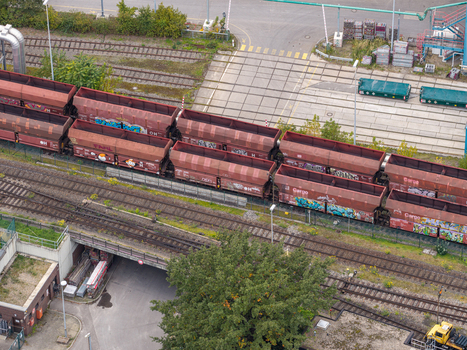 Aerial view of a freight train with graffiti covered cargo cars on tracks near the Heizkraftwerk Reuter West power plant in Berlin Berlin Germany.