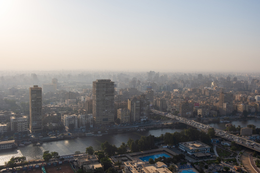 View of the bridge over the tranquil waterway and the buildings with their geometric patterns under the hazy sky Zamalek Cairo Governorate Egypt. View of the bridge over the tranquil waterway and the buildings with their geometric patterns under the hazy sky Zamalek Cairo Governorate Egypt.