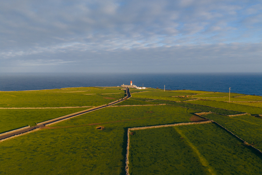 Aerial view of Farol de Albarnaz lighthouse on a cliff edge overlooking the Atlantic Ocean with green pastures and stone walls in Ponta Delgada Acores Portugal. Aerial view of Farol de Albarnaz lighthouse on a cliff edge overlooking the Atlantic Ocean with green pastures and stone walls in Ponta Delgada Acores Portugal.