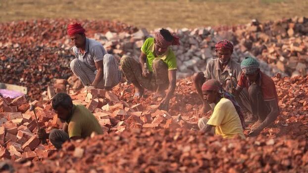 View of workers breaking bricks with hammers in a yard Bangladesh.