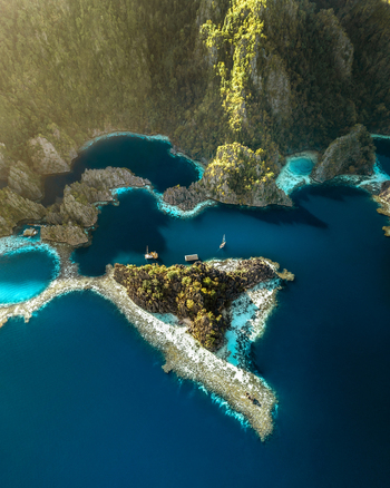 Aerial view of limestone karst formations and turquoise lagoons with boats in the clear blue water of Coron Mimaropa Philippines.