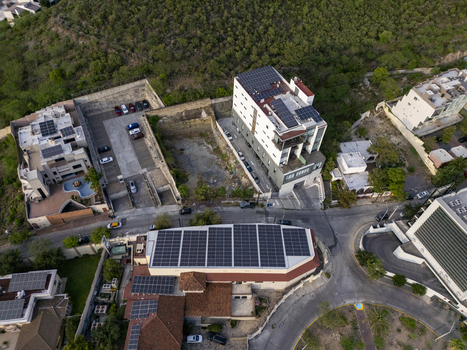 Aerial view of a modern building complex featuring extensive rooftop solar panels surrounded by urban streets parking areas and lush greenery in Monterrey Nuevo Leon Mexico. Aerial view of a modern building complex featuring extensive rooftop solar panels surrounded by urban streets parking areas and lush greenery in Monterrey Nuevo Leon Mexico.