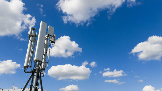 Aerial view of a telecommunications antenna array and cellular base station equipment against a bright blue sky with white clouds in Amsterdam North Holland Netherlands. Aerial view of a telecommunications antenna array and cellular base station equipment against a bright blue sky with white clouds in Amsterdam North Holland Netherlands.
