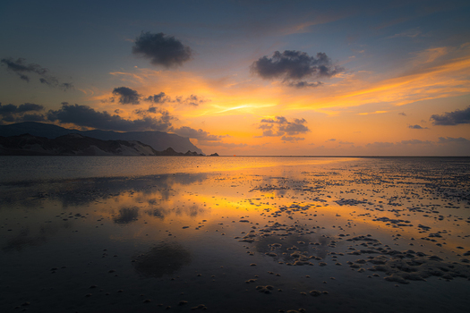 View of the sunset reflecting on the calm waters of Detwah Lagoon with mountains in the background Qalansiyah wa Abd Al Kuri Socotra Yemen. View of the sunset reflecting on the calm waters of Detwah Lagoon with mountains in the background Qalansiyah wa Abd Al Kuri Socotra Yemen.