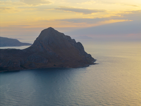 Aerial view of the rocky silhouette of Monte Cofano rising above the calm Mediterranean sea during a golden sunset Palermo Sicily Italy. Aerial view of the rocky silhouette of Monte Cofano rising above the calm Mediterranean sea during a golden sunset Palermo Sicily Italy.