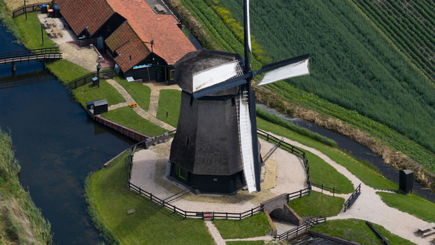 Aerial view of De Museummolen windmill surrounded by green fields a canal and a historic building in Schermerhorn Noord Holland Netherlands. Aerial view of De Museummolen windmill surrounded by green fields a canal and a historic building in Schermerhorn Noord Holland Netherlands.