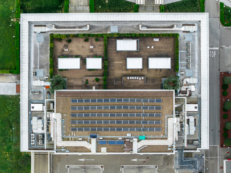 Aerial view of a modern building roof featuring solar panels HVAC systems and a wooden terrace with green hedges in Leccio Toscana Italy. Aerial view of a modern building roof featuring solar panels HVAC systems and a wooden terrace with green hedges in Leccio Toscana Italy.