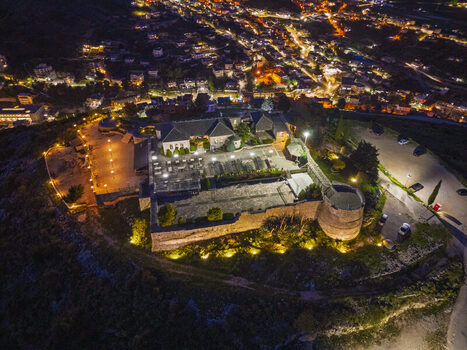 Aerial view of Lekuresi Castle illuminated at night featuring stone walls a circular tower and the surrounding city lights of Saranda Vlore County Albania. Aerial view of Lekuresi Castle illuminated at night featuring stone walls a circular tower and the surrounding city lights of Saranda Vlore County Albania.