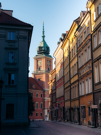 View of the historic Royal Castle tower rising above the colorful buildings and cobblestone streets of the Old Town in Warsaw Masovian Voivodeship Poland. View of the historic Royal Castle tower rising above the colorful buildings and cobblestone streets of the Old Town in Warsaw Masovian Voivodeship Poland.