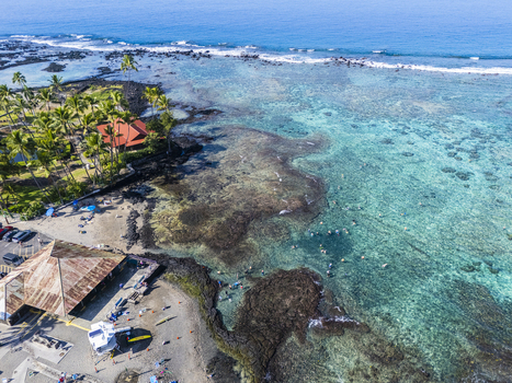Aerial view of Kahalu u Beach Park featuring turquoise waters vibrant coral reefs and people snorkeling along the palm fringed coastline in Kailua Kona Hawaii United States. Aerial view of Kahalu u Beach Park featuring turquoise waters vibrant coral reefs and people snorkeling along the palm fringed coastline in Kailua Kona Hawaii United States.