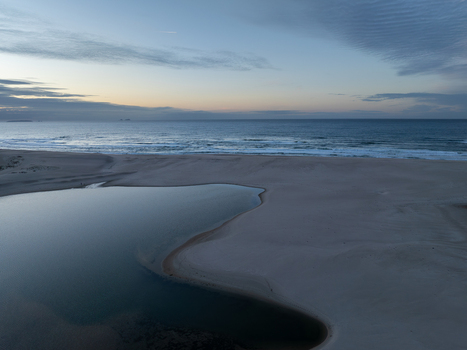 Aerial view of Lagoa de Obidos meeting the Atlantic Ocean across a wide sandy beach under a soft twilight sky in Foz do Arelho Leiria District Portugal. Aerial view of Lagoa de Obidos meeting the Atlantic Ocean across a wide sandy beach under a soft twilight sky in Foz do Arelho Leiria District Portugal.