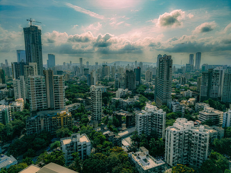 Aerial view of the Mumbai skyline featuring modern skyscrapers and residential towers nestled among dense green trees under a cloudy sky Mumbai Maharashtra India. Aerial view of the Mumbai skyline featuring modern skyscrapers and residential towers nestled among dense green trees under a cloudy sky Mumbai Maharashtra India.