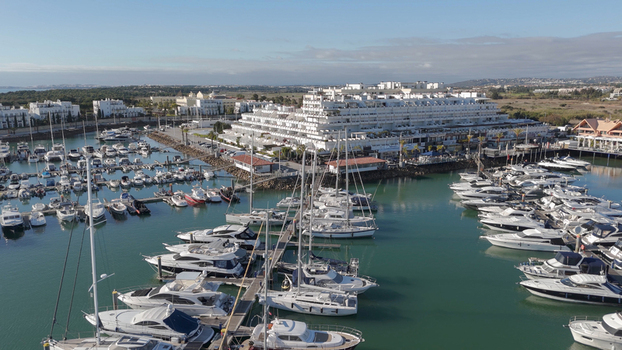 Aerial view of Vilamoura marina with numerous luxury yachts and boats docked in the harbor surrounded by white resort buildings in Quarteira Faro District Portugal.
