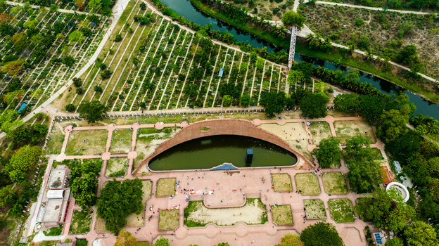 Aerial view of the Rayer Bazaar Martyred Intellectuals Memorial with its curved brick wall and reflecting pool surrounded by greenery and pathways in Dhaka Dhaka Division Bangladesh.