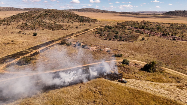 Aerial view of a controlled firebreak burn in the savanna with a vehicle nearby dry grass and rolling hills in the background in Modimolle Limpopo South Africa. Aerial view of a controlled firebreak burn in the savanna with a vehicle nearby dry grass and rolling hills in the background in Modimolle Limpopo South Africa.