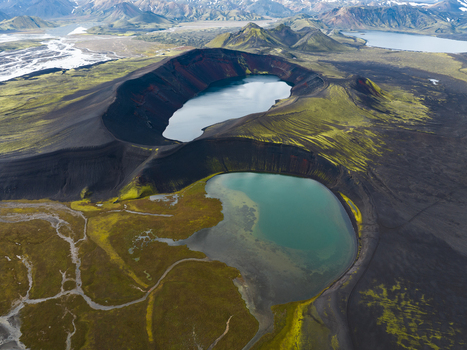 Aerial view of twin volcanic craters embrace serene lakes under Iceland s vast sky a stark contrast of dark earth and vibrant waters Highlands Iceland.