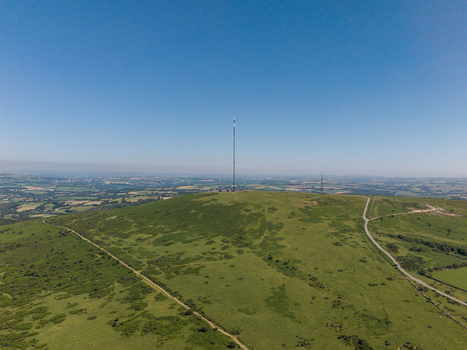Aerial view of the Caradon Hill transmitting station mast standing on the grassy slopes of the moorland in Minions Cornwall United Kingdom. Aerial view of the Caradon Hill transmitting station mast standing on the grassy slopes of the moorland in Minions Cornwall United Kingdom.