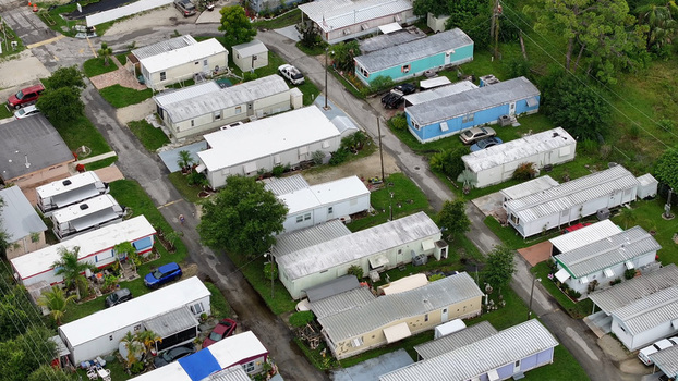 Aerial view of a mobile home park with rows of manufactured houses paved streets and green lawns in Cape Coral Florida United States.
