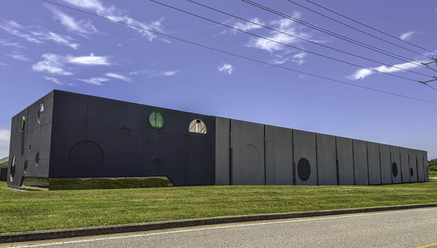 View of the Csquare Data Center featuring modern dark and light grey paneling with circular architectural accents and green vents under a clear blue sky in Gallatin Tennessee United States. View of the Csquare Data Center featuring modern dark and light grey paneling with circular architectural accents and green vents under a clear blue sky in Gallatin Tennessee United States.