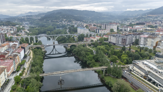 Orense Spain 30 April 2026 Aerial view of the Ponte Nova bridge spanning the Mino River with historic buildings and lush greenery under an overcast sky.