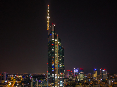 Aerial view of the illuminated Varso Tower skyscraper at night with its glowing spire rising above the dark Warsaw city skyline in Poland. Aerial view of the illuminated Varso Tower skyscraper at night with its glowing spire rising above the dark Warsaw city skyline in Poland.