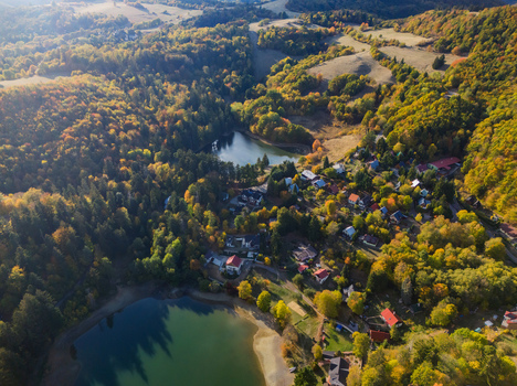 Aerial view of Velka Vindsachta and Evickino lakes surrounded by dense autumn forests and small village houses in Stiavnicke Bane Banskobystricky kraj Slovakia.
