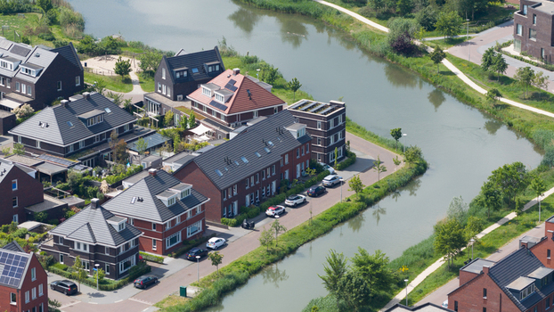 Aerial view of modern residential houses with dark roofs and solar panels along a winding canal Utrecht Utrecht Netherlands. Aerial view of modern residential houses with dark roofs and solar panels along a winding canal Utrecht Utrecht Netherlands.