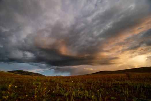 View of dramatic storm clouds over the Sacred Valley at sunset with golden light illuminating the rolling hills and grassy fields in Urubamba Province Cusco Peru. View of dramatic storm clouds over the Sacred Valley at sunset with golden light illuminating the rolling hills and grassy fields in Urubamba Province Cusco Peru.