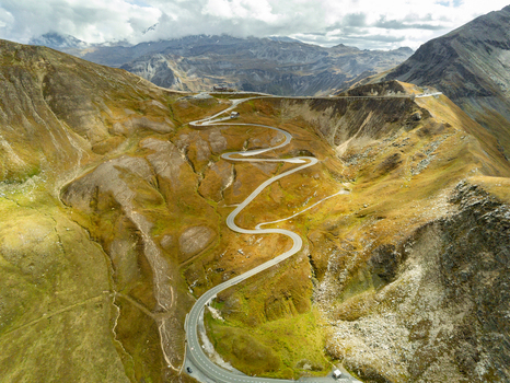 Aerial view of Grossglockner High Alpine Road winding through the rugged alpine landscape with rocky slopes and mountain peaks under a cloudy sky Zell am See District Salzburg Austria.