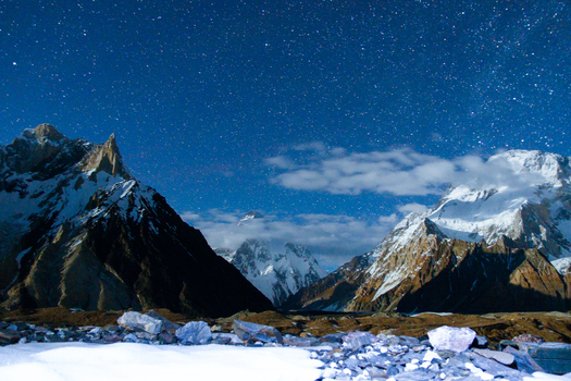 View of the snow capped K2 mountain peak under a clear starry night sky with wispy clouds Skardu Gilgit Pakistan.