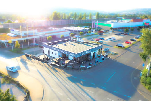 Forchheim Germany 11 March 2026 Aerial view of the Kleine Pause GmbH restaurant building with its outdoor terrace and surrounding parking area under bright sunlight.