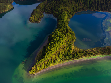 Aerial view of Lagoa do Fogo featuring a lush forested peninsula extending into the turquoise volcanic crater lake in Agua de Alto Azores Portugal. Aerial view of Lagoa do Fogo featuring a lush forested peninsula extending into the turquoise volcanic crater lake in Agua de Alto Azores Portugal.