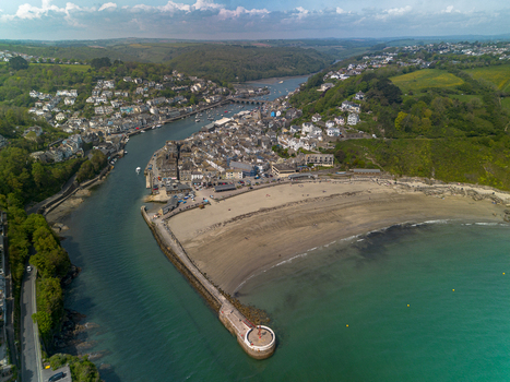 Aerial view of the harbour sandy beach stone pier and surrounding green hills of the coastal town in Looe Cornwall United Kingdom. Aerial view of the harbour sandy beach stone pier and surrounding green hills of the coastal town in Looe Cornwall United Kingdom.