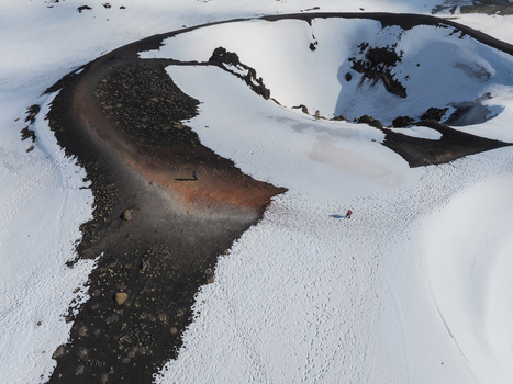 Aerial view of the snow covered volcanic crater on the south slope of Mount Etna with people walking along a trail in Nicolosi Sicilia Italy. Aerial view of the snow covered volcanic crater on the south slope of Mount Etna with people walking along a trail in Nicolosi Sicilia Italy.