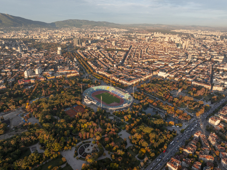 Aerial view of Vasil Levski National Stadium surrounded by autumn trees in a park with the cityscape of Sofia in the background in Sofia Sofia City Province Bulgaria. Aerial view of Vasil Levski National Stadium surrounded by autumn trees in a park with the cityscape of Sofia in the background in Sofia Sofia City Province Bulgaria.