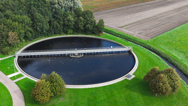 Aerial view of a circular water treatment tank surrounded by green grass and agricultural fields in Warmenhuizen North Holland Netherlands. Aerial view of a circular water treatment tank surrounded by green grass and agricultural fields in Warmenhuizen North Holland Netherlands.